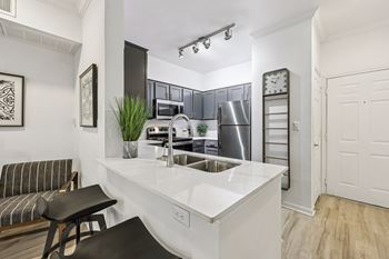 A kitchen with a white countertop and a black stool.